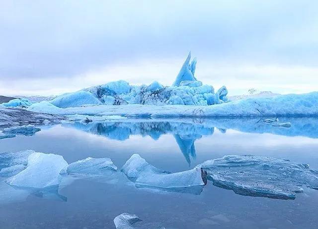 ภูเขาน้ำแข็งสีฟ้าลอยสะท้อนเงาบนผิวน้ำนิ่งของ Jökulsárlón