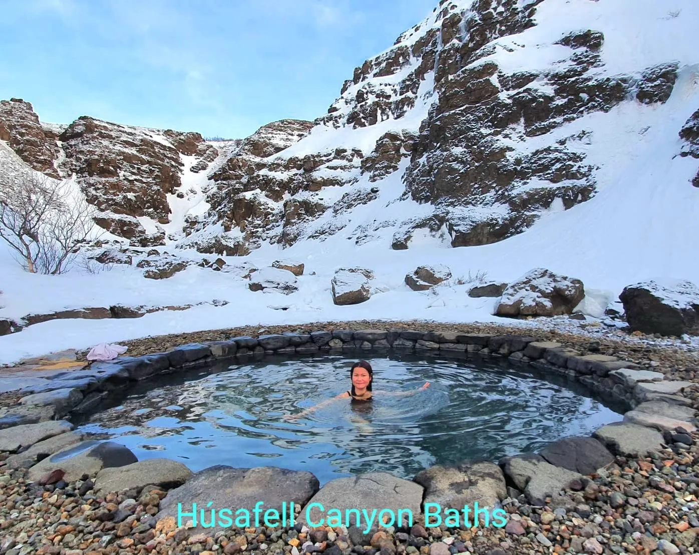 บ่อน้ำอุ่นทรงกลมในหุบเขาหินปกคลุมหิมะที่ Húsafell Canyon Baths
